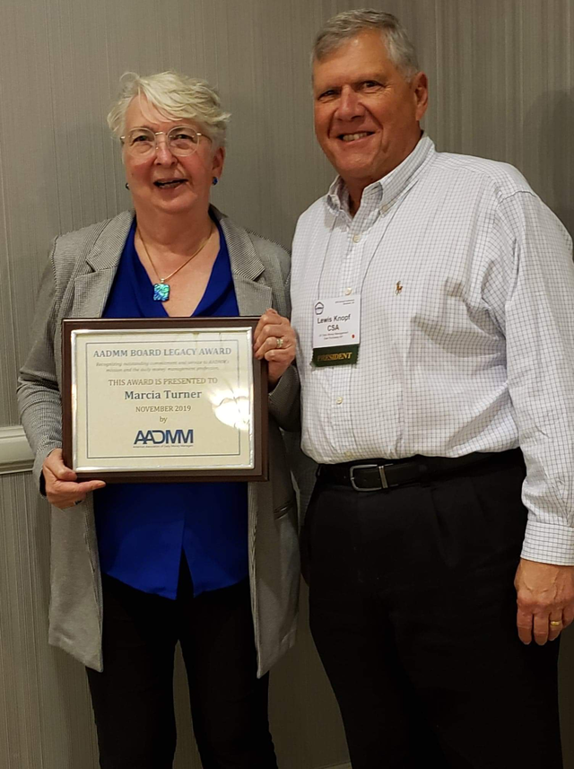 Marcia holding her AADMM Board Legacy Award plaque